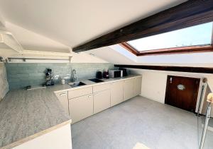 a kitchen with white cabinets and a skylight at Spa Privatif Montataire in Montataire