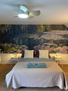 a bedroom with a bed with a painting on the wall at Maison Floréal Giverny in Giverny