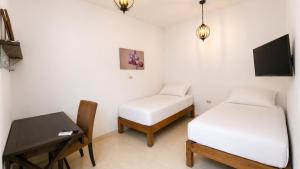 a room with two beds and a table and a desk at Casa Bugambilias in Tenosique de Pino Suárez
