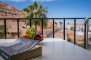 a book with a bowl of fruit on top of a balcony at Noemi Blu Tenerife in Los Cristianos