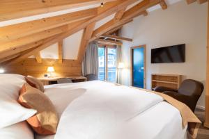 a bedroom with a white bed and a tv at Hotel Albris in Pontresina
