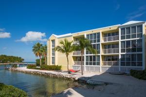a building with palm trees next to a body of water at Bluegreen Vacations Hammocks at Marathon, Ascend Collection Resort in Marathon
