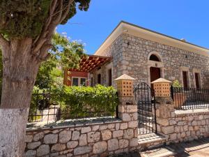 a stone house with a fence and a tree at Villa To Petrino in Vathís