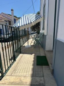 a patio with an umbrella and a green rug at Casa tio Manuel in São Martinho das Amoreiras