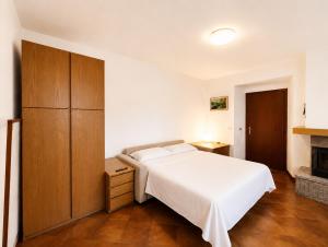 a bedroom with a white bed and a wooden cabinet at Casa Leima - Larihome A83 in Gera Lario +7 photos