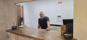 a man with a long beard standing behind a counter at Havana Hostel in Albufeira