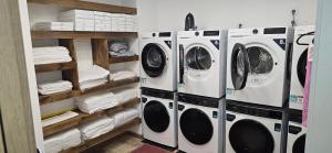 a laundry room with three washing machines and towels at Havana Hostel in Albufeira
