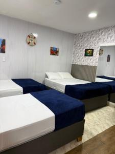a bedroom with three beds with blue and white sheets at Hospedaje Parque Central frente al parque principal in Santa Rosa de Cabal +15 photos