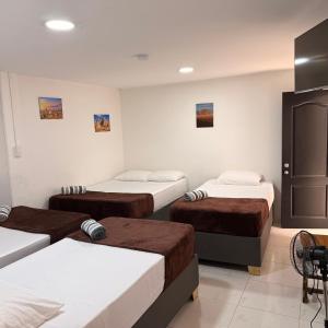 a room with three beds in a room at Hospedaje Parque Central frente al parque principal in Santa Rosa de Cabal