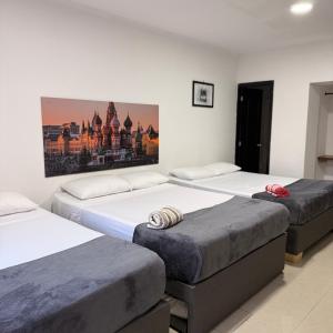 three beds sitting in a room with a painting on the wall at Hospedaje Parque Central frente al parque principal in Santa Rosa de Cabal