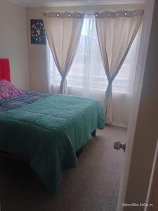 a bedroom with a bed and a window with curtains at M&L departamento in Limache