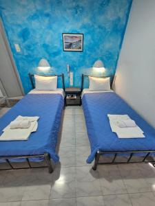 two beds in a room with blue walls at Hotel Palladion in Karterados