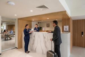 a man and two women standing at a counter at Palmetto Hotel Business San Borja in Lima