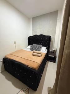 a bedroom with a large bed with a black headboard at My Humble Home in Dipolog