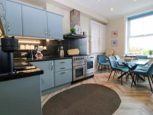 a kitchen with blue cabinets and a table with chairs at Jack's House in Tywyn