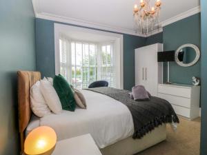 a bedroom with a bed with blue walls and a chandelier at Jack's House in Tywyn