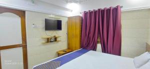 a bedroom with a bed with purple curtains and a tv at Universal Inn in Chennai