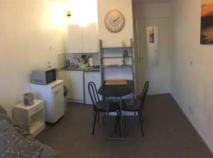 a small kitchen with a table and chairs and a clock at Studio BRITTANY in Chambéry +9 photos