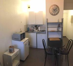 a small kitchen with a table and a clock on the wall at Studio BRITTANY in Chambéry