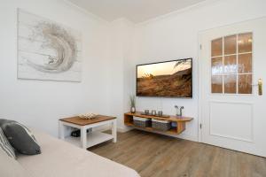 a white room with a bed and a table and a door at Syltliebe in Westerland