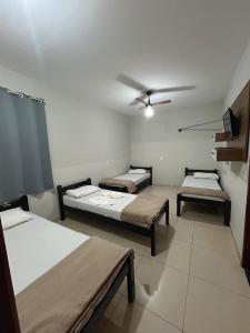 a room with three beds and a ceiling fan at Hotel 2001 in Iraí de Minas