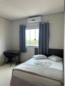 a bedroom with a bed with a desk and a window at Hotel 2001 in Iraí de Minas