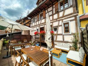 a balcony with a wooden table and chairs and a building at Le Cottage Bleu- In the Heart of Riquewihr by La Maison Bleue in Riquewihr