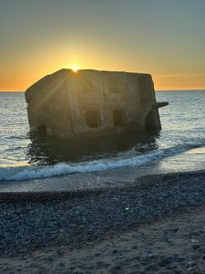 a rock in the water on a beach at sunset at Peaceful haven in Liepāja