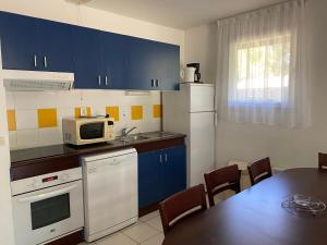 a kitchen with blue cabinets and a table with a microwave at Fre&dom in Lacanau