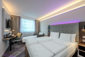 a hotel room with a large white bed and a desk at Premier Inn Wolfsburg City Centre in Wolfsburg