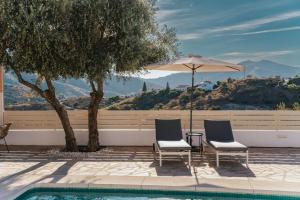 two chairs and a table with an umbrella next to a pool at B&B Casa Mijo in Daimalos +26 photos