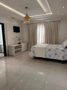 a bedroom with a bed and a chandelier at Mansão Bolsoni in Saquarema