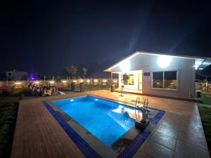 a swimming pool in front of a house at night at La Vida Estate Farm in Garhmuktesar