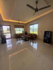 a living room with a ceiling fan and a tv at La Vida Estate Farm in Garhmuktesar