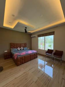a bedroom with a bed and two chairs and a window at La Vida Estate Farm in Garhmuktesar +27 photos