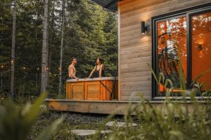 a man and woman sitting in a bath tub on a house at Chalet la coulée douce, Expérience thermale privée in Saint Come