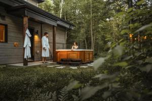 a man and woman standing next to a hot tub on a house at Chalet la coulée douce, Expérience thermale privée in Saint Come