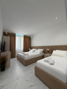 a hotel room with three beds and a television at Hotel Djakbe in Tirana