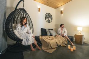 a man and a woman sitting in a swing at Chalet la coulée douce, Expérience thermale privée in Saint Come