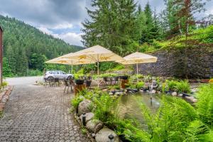 a patio with tables and umbrellas next to a pond at Hotel Velveta in Špindlerův Mlýn