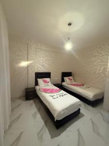 two beds in a room with white tile floors at Licht & ruim 2-slaapkamer appartement met airco & Wifi - rustig wijk Marrakesh in Marrakesh
