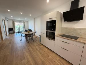 a kitchen with white cabinets and a table and a dining room at Charmant appartement sur les hauteurs d'Erbalunga in Brando