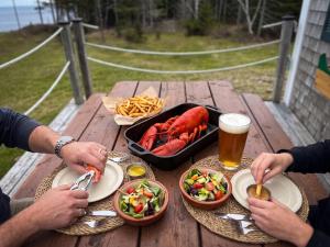 two people sitting at a picnic table with food and beer at Ocean Pines seaside cottage in Shelburne +28 photos