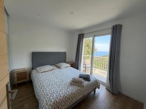 a bedroom with a bed and a large window at Charmant appartement sur les hauteurs d'Erbalunga in Brando