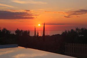 a sunset over the ocean with a swimming pool at Ionian Harmony Luxury Villas in Tsoukalades