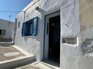 a white building with a blue door and window at John's View in Serifos Chora