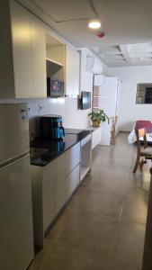 a kitchen with white cabinets and a black counter top at #5 Monoambiente, Pool, Grill, Gym, Sauna in Nu Guazu
