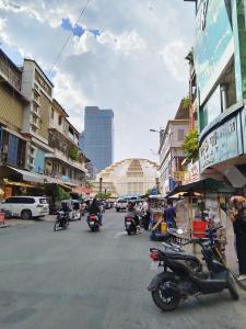 a group of people riding motorcycles down a city street at Monica's house in Phnom Penh