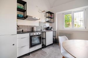 a kitchen with white cabinets and a table and a window at Ca del Lac, few steps from Lake Maggiore in Porto Valtravaglia