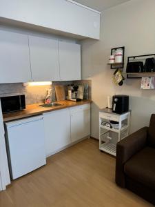 a kitchen with white cabinets and a couch in a room at Hotelli Terme 111 in Kilvakkala